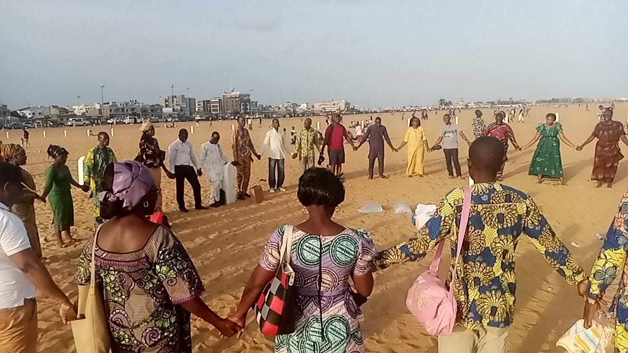A group of people holding hands on the beach.